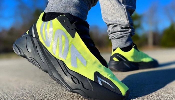 Tênis Yeezy Boost 700 MNVN Phosphor amarelo neon com detalhes pretos e logo refletivo “700” prateado.