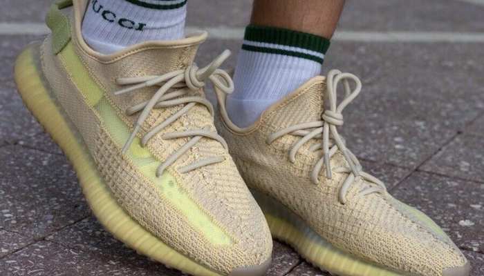 Tênis Yeezy Boost 350 V2 Flax em Primeknit bege com faixa lateral amarela translúcida.