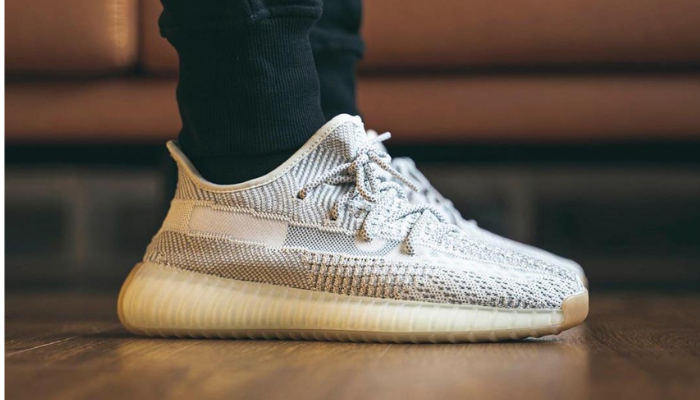 Tênis Yeezy Boost 350 V2 Yeshaya branco e cinza com sola translúcida.