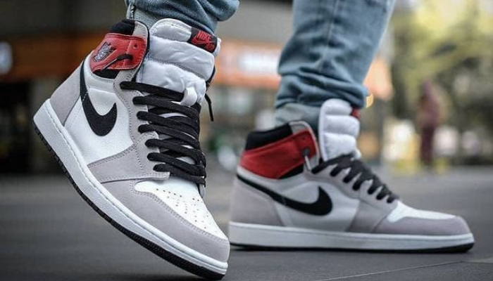 Air Jordan 1 High Smoke Grey em couro branco e camurça cinza com detalhes em preto e vermelho.