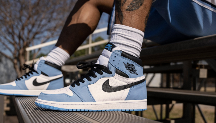 Air Jordan 1 High University Blue com base branca, camurça azul e detalhes em preto.
