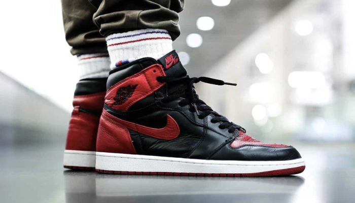 Air Jordan 1 Mid GS Banned preto e vermelho com solado vermelho e logotipo Wings clássico.