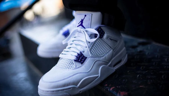 Tênis Air Jordan 4 Purple Metallic branco com detalhes metálicos roxos e logo Jumpman.