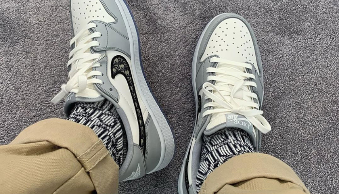 Tênis Dior x Air Jordan 1 Low branco e cinza com Swoosh Dior Oblique e sola translúcida.