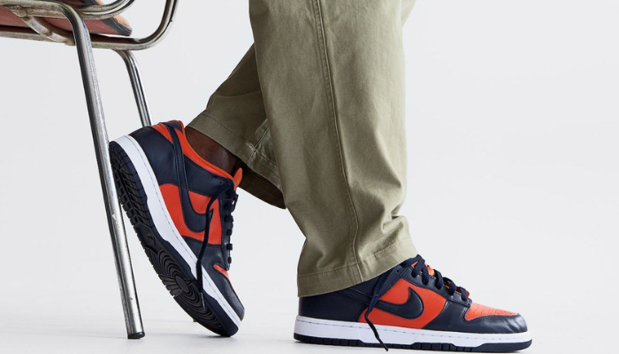 Tênis Nike Dunk Low SP Champ Colors em couro laranja e azul com Swoosh branco.