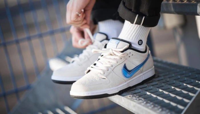 Tênis Nike SB Dunk Low Truck It em camurça bege com Swoosh azul e sola preta.