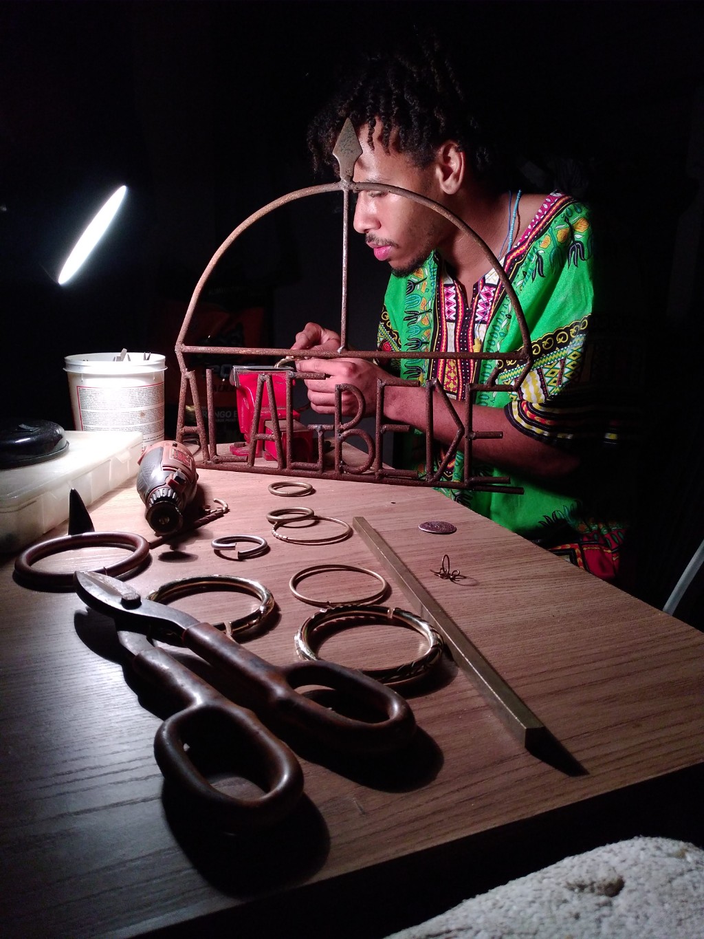 Eduardo forjando um ornamento com o arco de Oxóssi e o nome Alagbede