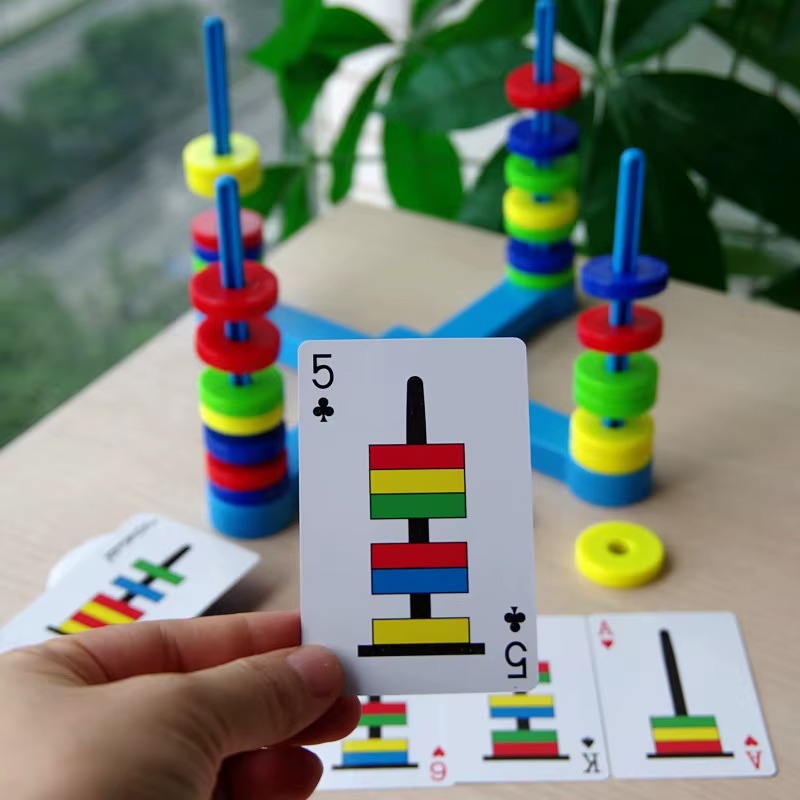 Jogo educativo C&eacute;rebro Magn&eacute;tico com pe&ccedil;as coloridas empilhadas em suportes azuis e cartas ilustrando as combina&ccedil;&otilde;es para montar - Barraco Velho