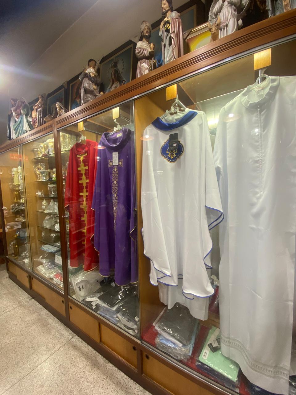 Vitrine de paramentos litúrgicos da Livraria Santa Fé: casulas vermelha, roxa, branca e azul para todas as celebrações
