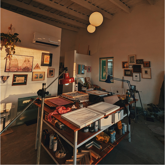 Interior del taller con mesa de trabajo y cuadros en las paredes