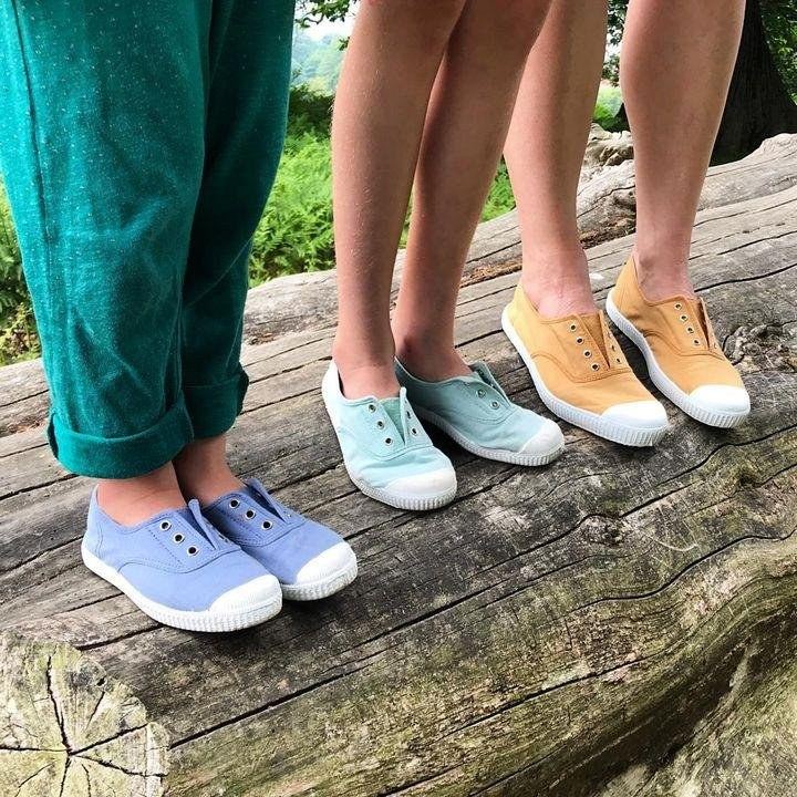 Chicos parados sobre un tronco con zapatillas Cienta de colores