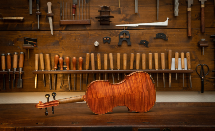 Bancada de luthieria da Mega Música em Curitiba, com ferramentas e violino para regulagem e reparos