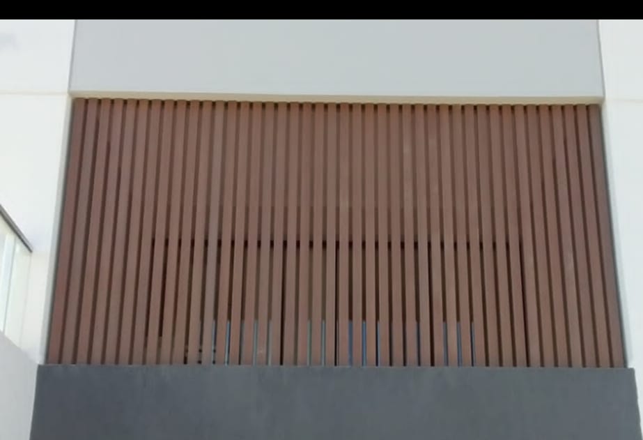 Celosía de columnas WPC símil madera colocadas en vertical delante de una abertura de la fachada