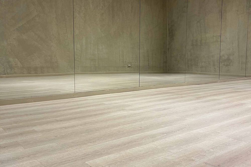 Piso flotante HDF símil madera en tono claro instalado en un salón con espejos