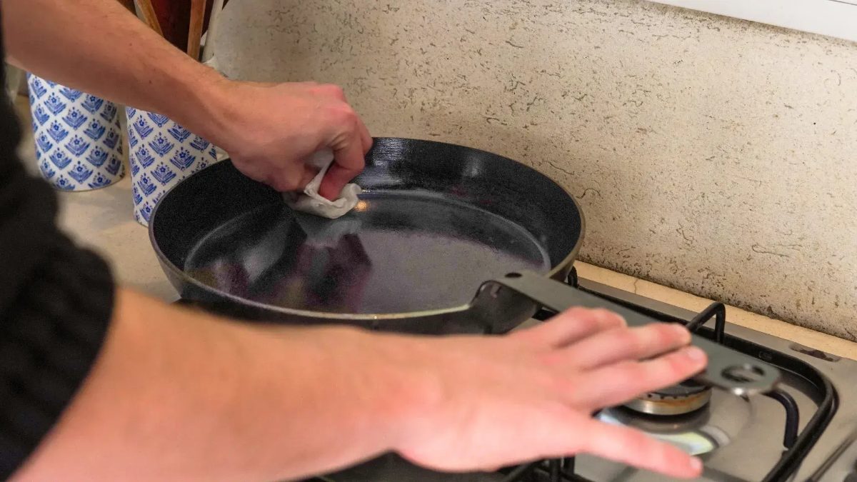 Frigideira de aço carbono recebendo uma camada fina de óleo com papel