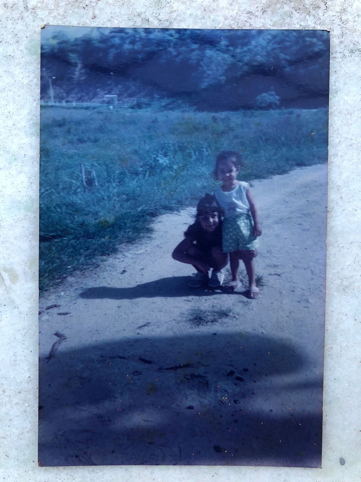 Duas crianças em um caminho de terra, em fotografia do acervo da marca.