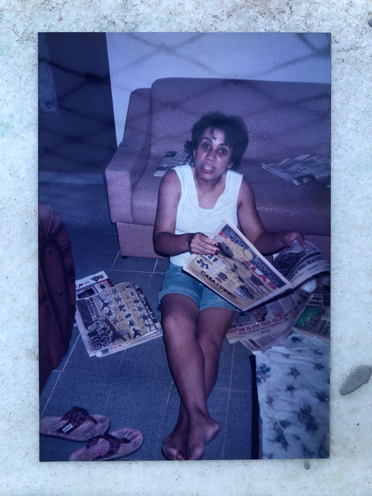 Mulher sentada com uma revista aberta no colo, em fotografia de família.