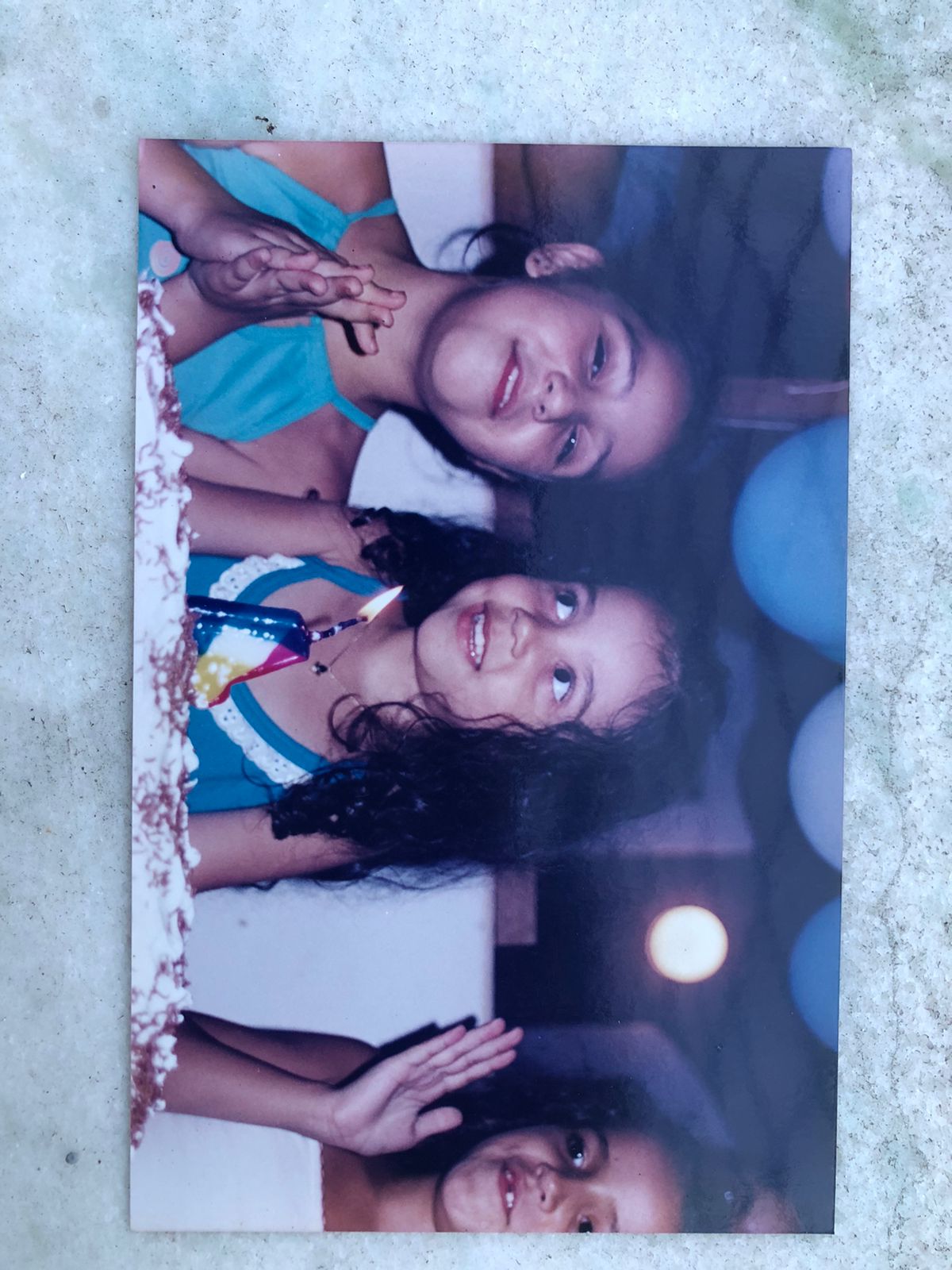 Crianças reunidas diante de um bolo de aniversário.