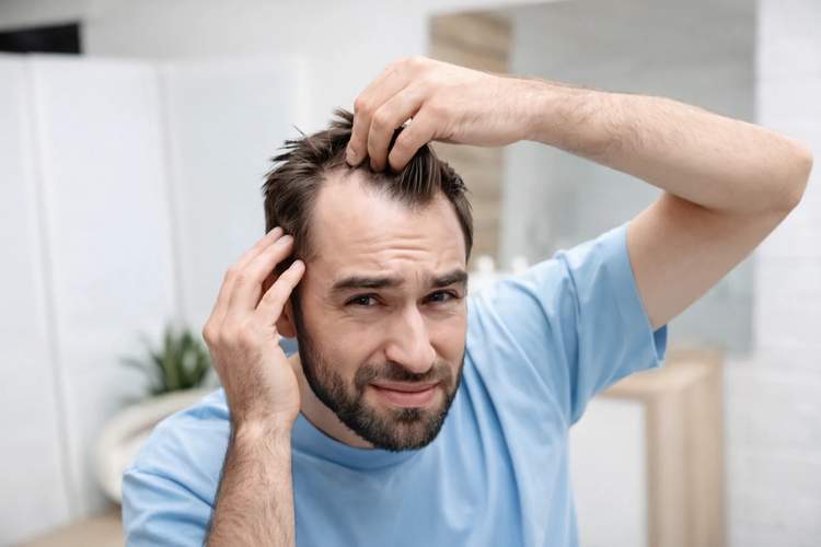 Hombre mirando su ca&iacute;da de cabello
