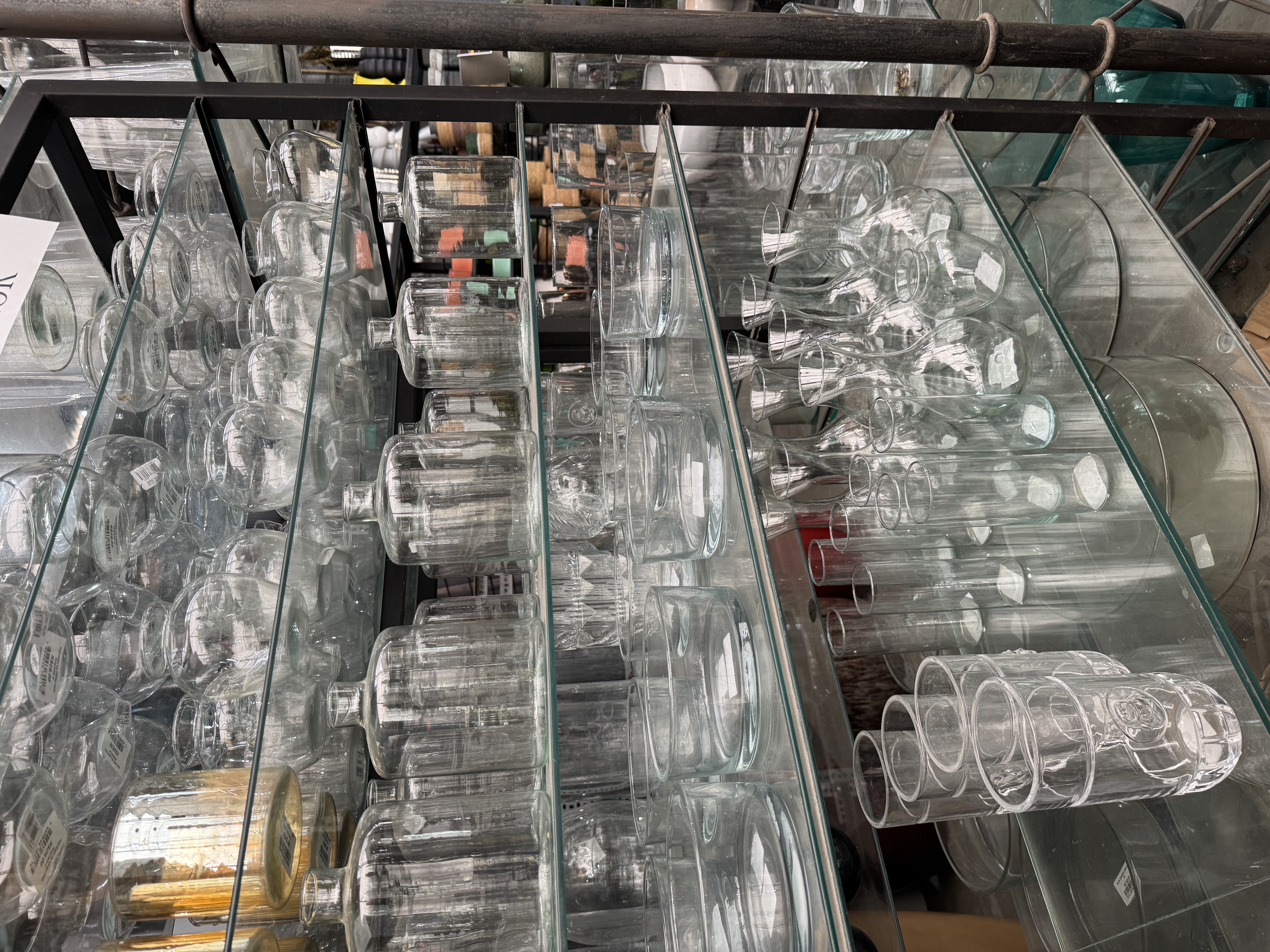 Prateleiras de vidraria e vasos de vidro na loja física Tutoia Flores