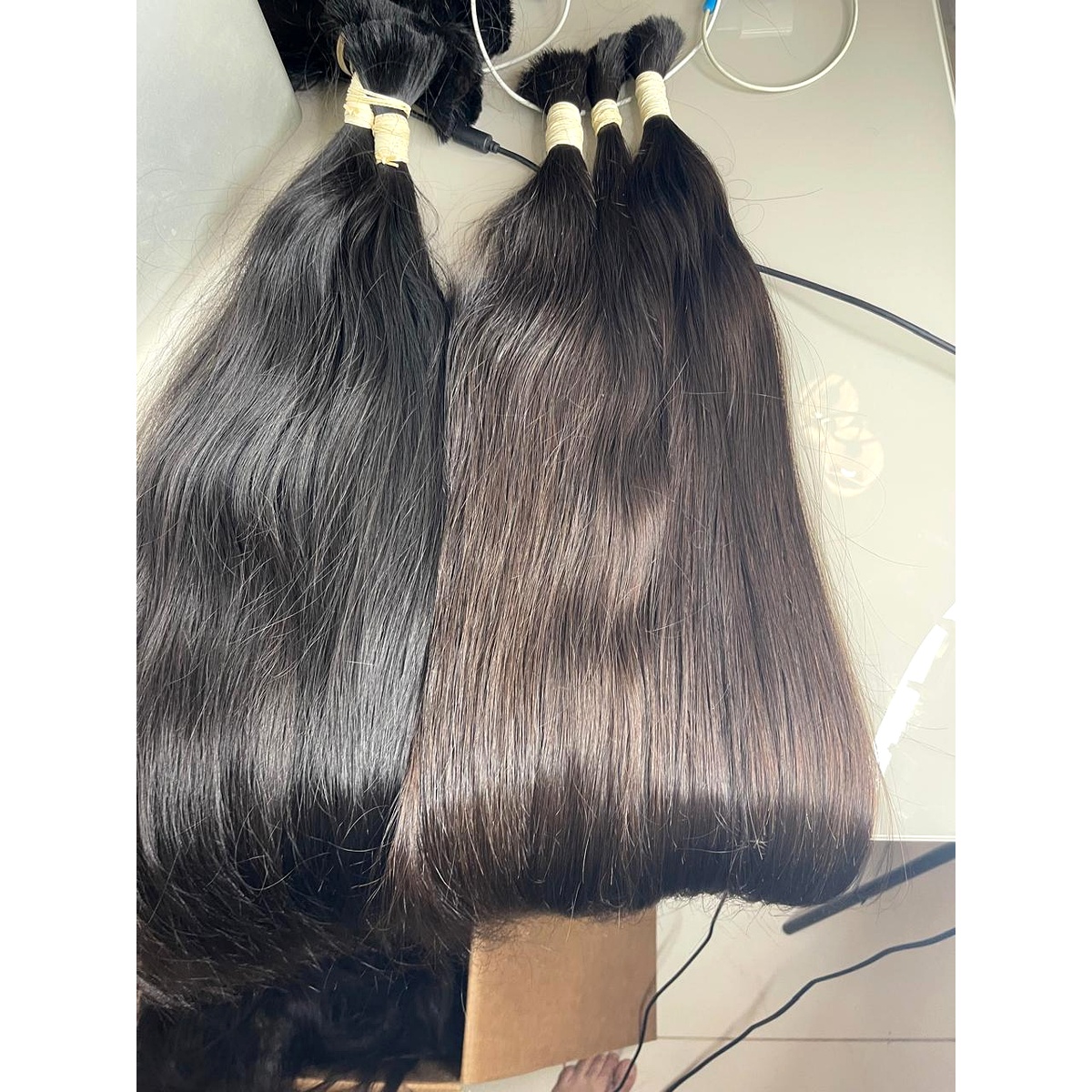 Duas mechas de cabelo peruano andino castanho escuro lado a lado sobre a bancada, mostrando a variação natural de tom.