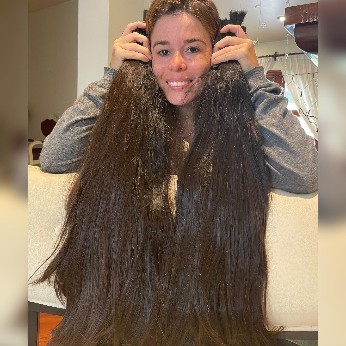 Marina segurando duas mechas de cabelo peruano andino castanho escuro, uma de cada lado do rosto.
