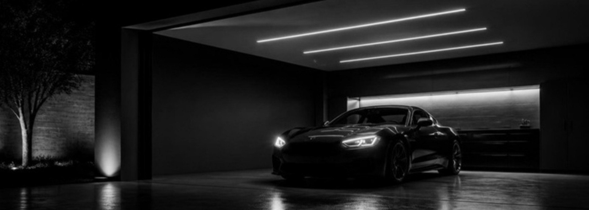 Carro com faróis LED acesos em garagem, em preto e branco