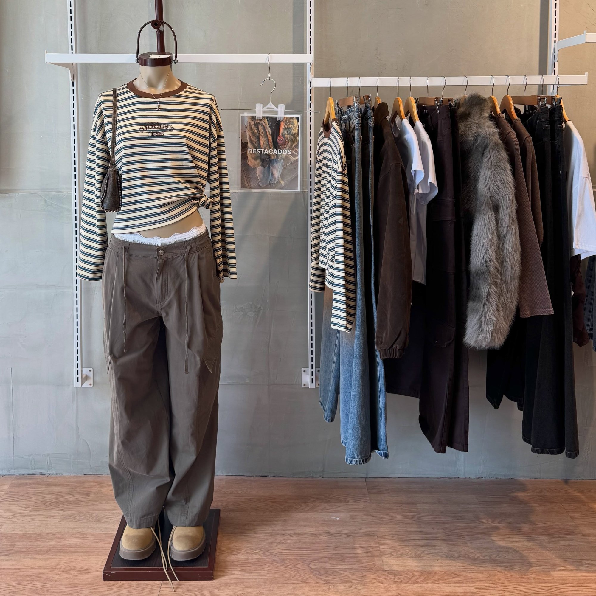 Maniquí con remera a rayas y pantalón ancho, al lado de un perchero con camperas y jeans