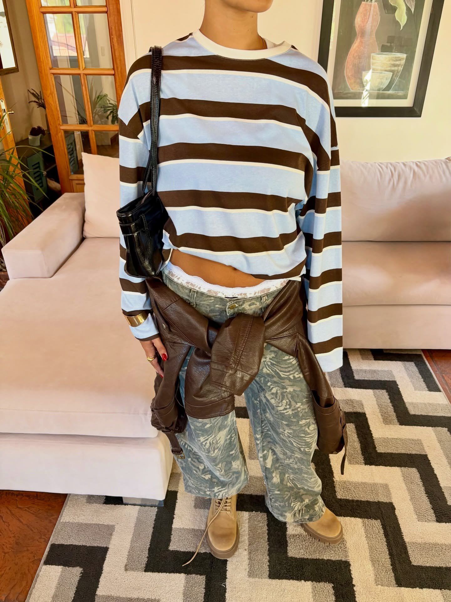 Pantalon cargo verde con sweater a rayas atado a la cintura y top marron