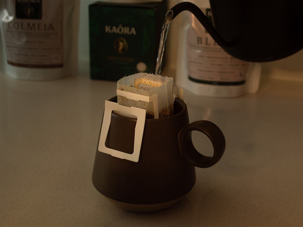 Agua caliente vertida sobre un sobre de Drip Coffee colgado en una taza