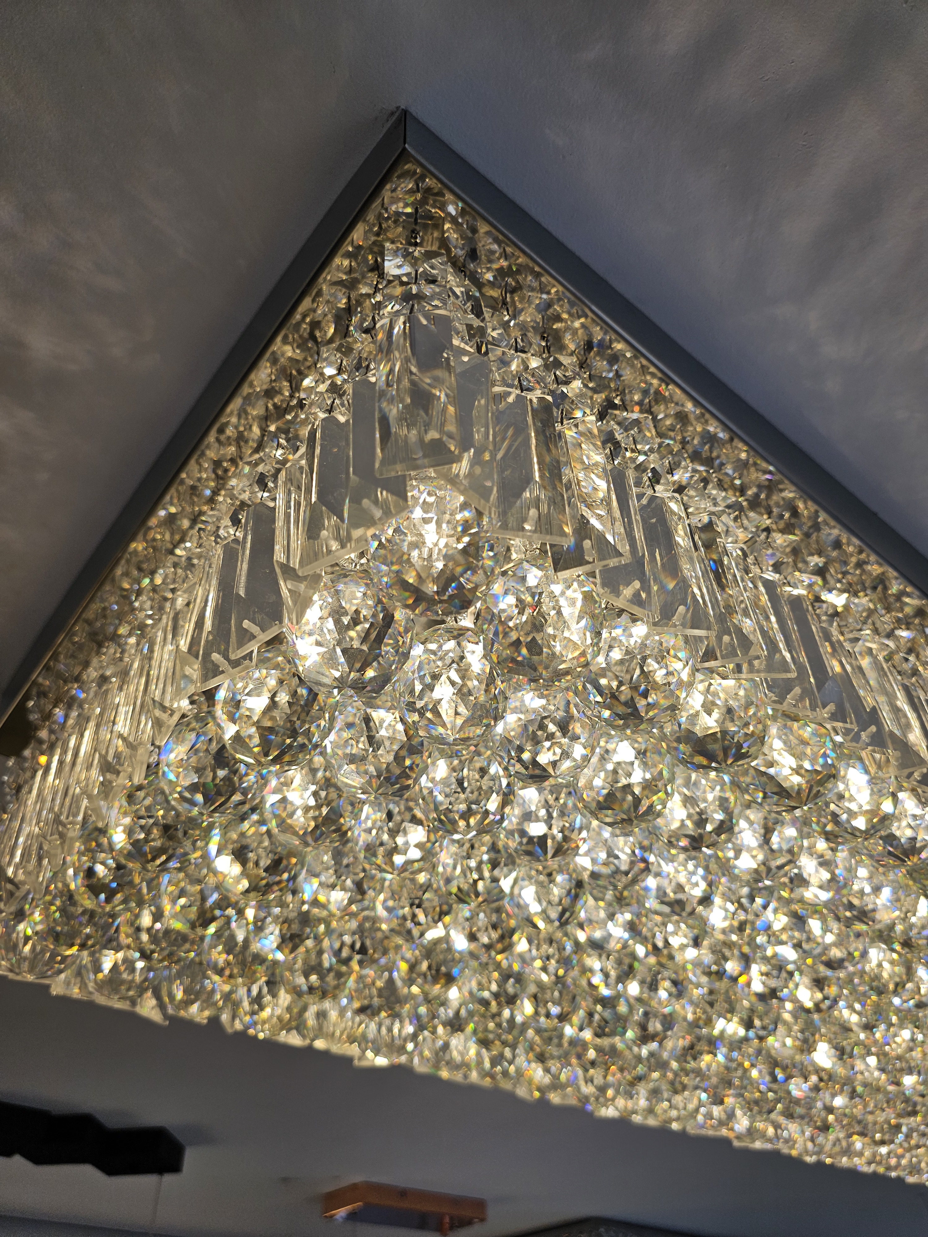 Plafon de cristal retangular Zenith 100x40cm instalado no teto, com cristais brilhantes iluminando sala de jantar sofisticada.