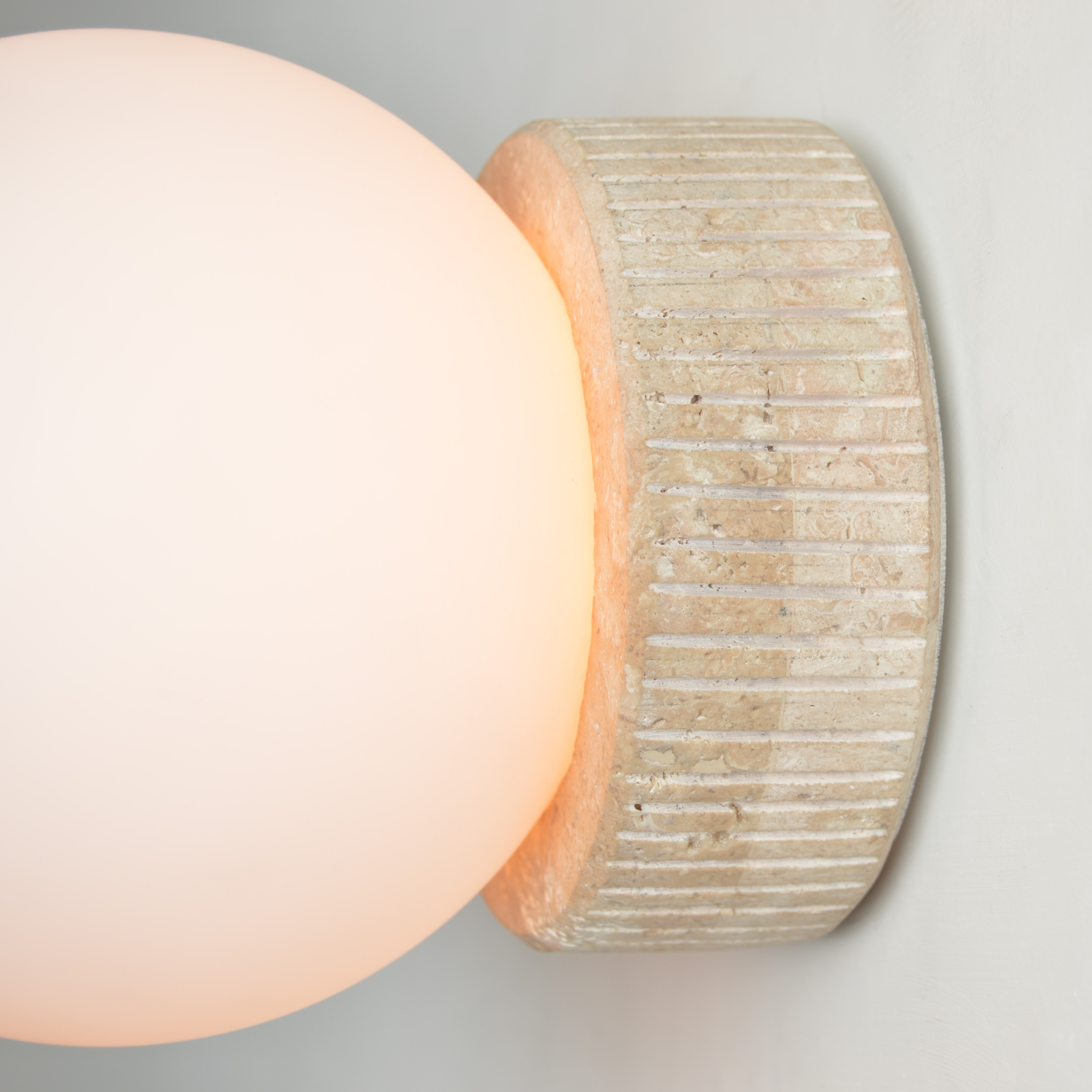 Luminária de parede resistente à água modelo Eclipse Ø40cm instalada em área externa com parede cinza, poltrona azul e plantas decorativas.