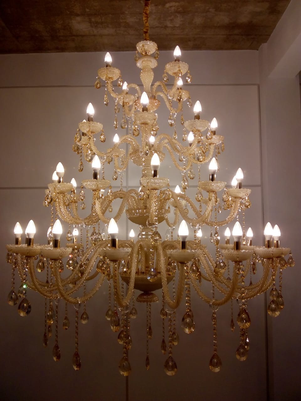 Lustre de cristal Maria Tereza com 42 braços e detalhes em cristais champagne, ideal para pé direito duplo e alto. Lustres Gênesis loja online de Lustres e Iluminação Decorativa
