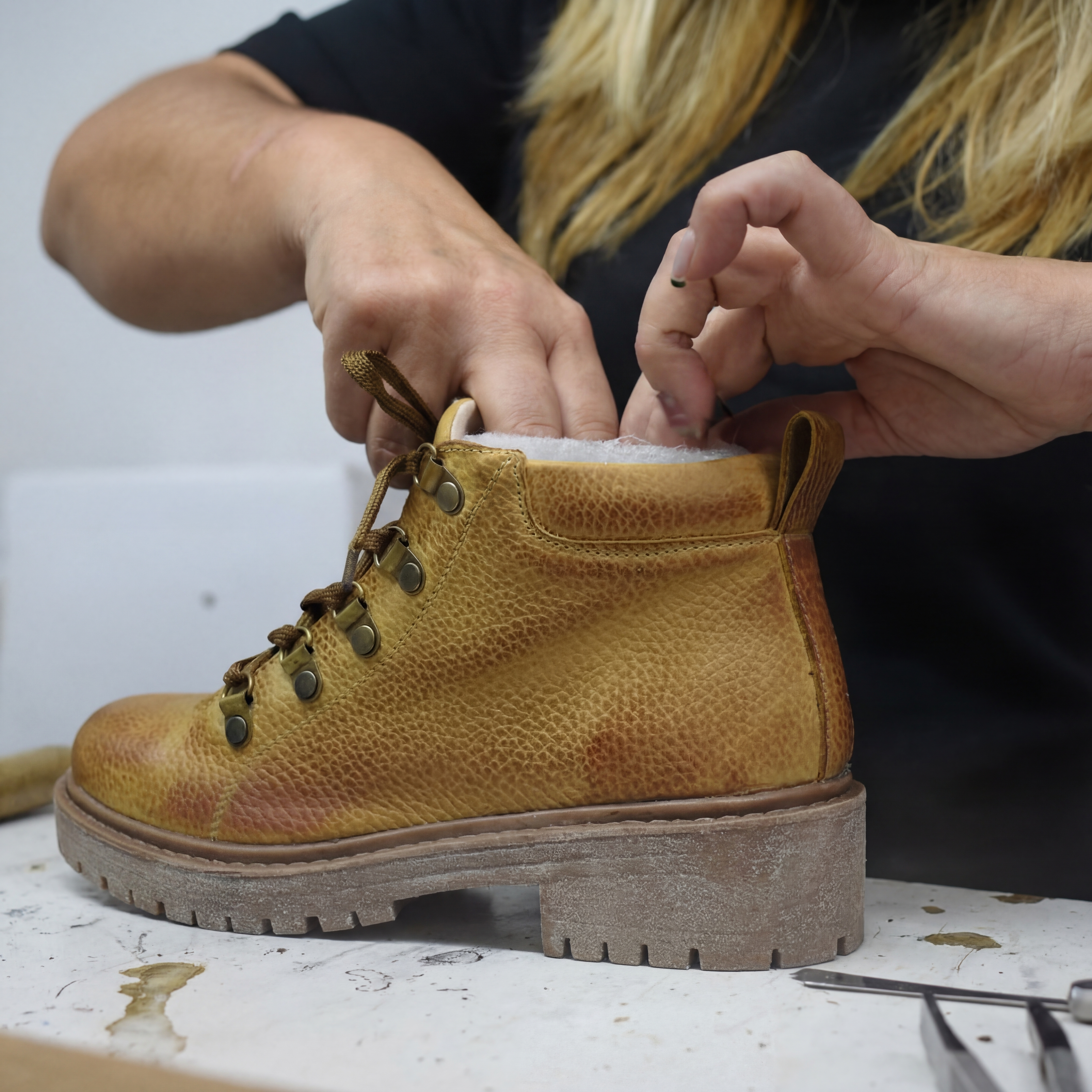 Modern footwear manufacturing facility with skilled craftsmen working on leather boots Argentine production